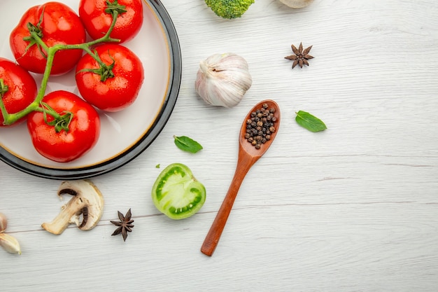 Draufsicht rote Tomaten auf Teller Knoblauch Pilz Anis schwarze Paprika in Holzlöffel Kopie Raum