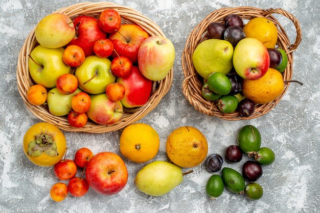 Draufsicht rote und gelbe Äpfel und Pflaumen Feykhoas Birnen und Kakis in den Weidenkörben und auch auf dem Boden