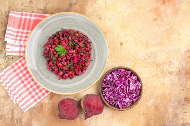 Draufsicht roter gesunder Salat mit Petersilienblättern aus Roter Bete und Schüssel mit gehacktem Kohl auf Holzhintergrund mit Kopienplatz