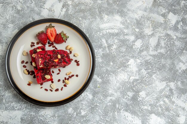 Draufsicht roter Nougat in Scheiben geschnitten mit Nüssen und frischen roten Erdbeeren auf weißer Oberfläche