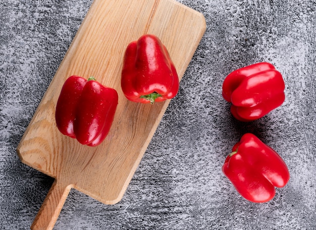 Kostenloses Foto draufsicht roter paprika pfeffer auf holzschneidebrett auf grauem stein horizontal