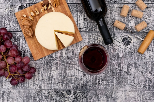 Draufsicht Rotwein mit Traube und Käse an Bord und auf weißem Holz horizontal