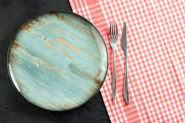 Draufsicht runde Platte Abendessen Messer und Gabel auf rot weiß karierten Tischdecke auf schwarzem Tisch