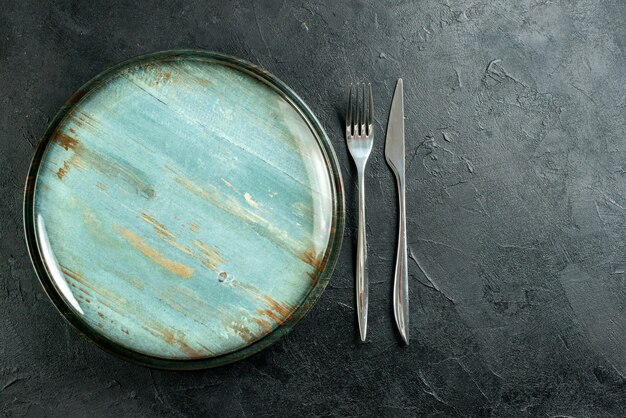 Draufsicht runde Platte Stahlgabel und Abendessenmesser auf schwarzem Tisch freien Platz