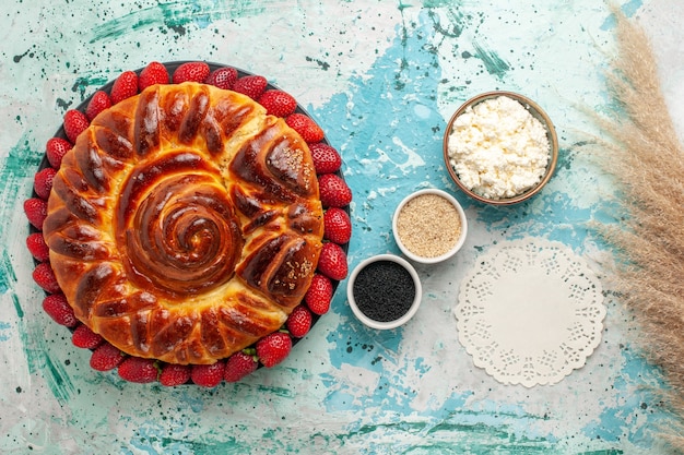 Draufsicht runder köstlicher kuchen gebackener und süßer kuchen mit erdbeeren auf blauer oberfläche