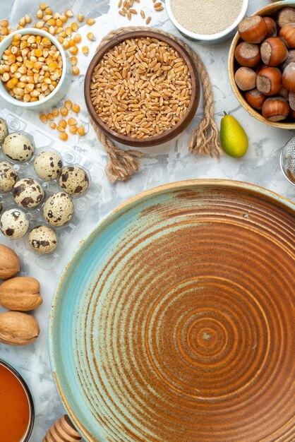 Draufsicht rundes Tablett mit Nüssen Mehl Brot Eier und Milch auf dem weißen Hintergrund Foto Farbe Kuchen Kuchenteig Hotcake Brötchen Keks