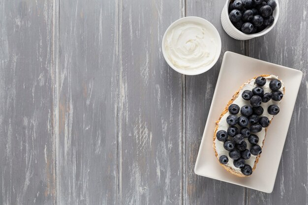 Draufsicht-Sandwich mit Frischkäse und Blaubeeren auf Teller mit Kopierraum