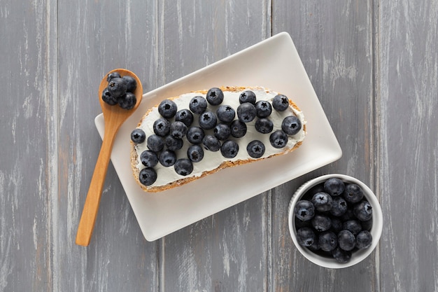 Kostenloses Foto draufsicht-sandwich mit frischkäse und blaubeeren auf teller mit löffel