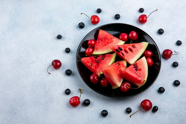 Draufsicht Scheiben der Wassermelone auf einem Teller mit Blaubeeren und Kirschen