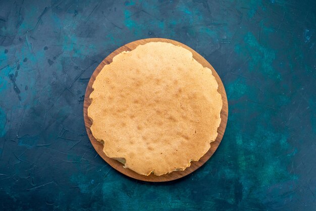 Draufsicht schlichter Kuchenteig, rund gebacken auf der dunkelblauen Oberfläche