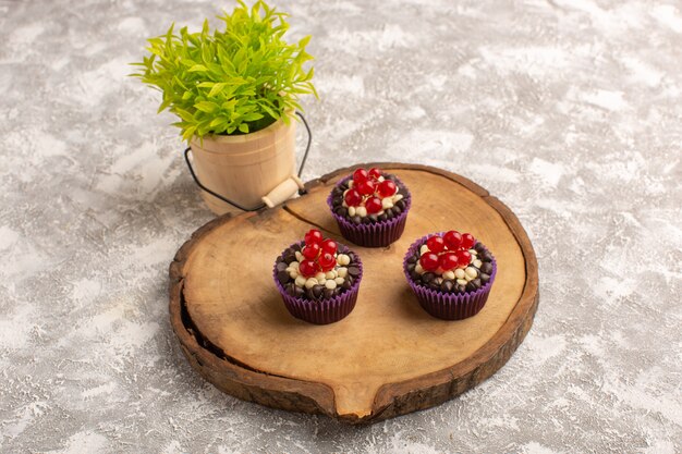 Draufsicht Schokoladen-Brownies mit Preiselbeeren auf dem hölzernen Schreibtisch mit Süßigkeiten und Pflanzenkuchenkeks süßer Backteig