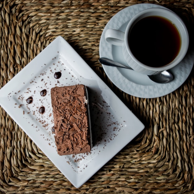 Draufsicht Schokoladen-Tiramisu mit Tasse Tee und weißem Teller und Löffel in Servietten