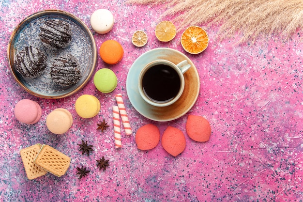 Draufsicht Schokoladenkuchen mit französischen Macarons auf hellrosa