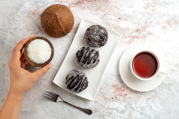 Draufsicht Schokoladenkuchen mit Tasse Tee und Kokosnuss auf weißer Oberfläche Schokoladenkuchen Kekszucker süßer Keks