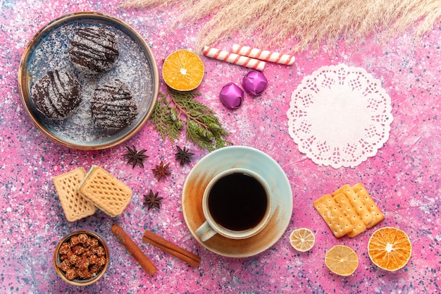 Draufsicht Schokoladenkuchen mit Waffeln und Tasse Tee auf Rosa