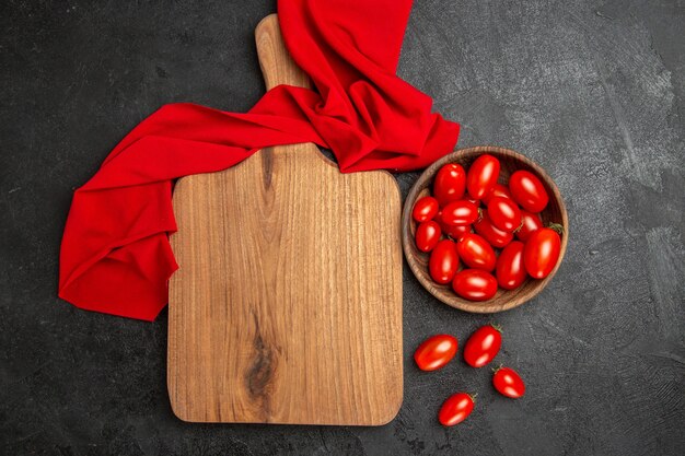 Draufsicht Schüssel mit Kirschtomaten rotes Handtuch ein Schneidebrett und Kirschtomaten auf dunklem Hintergrund