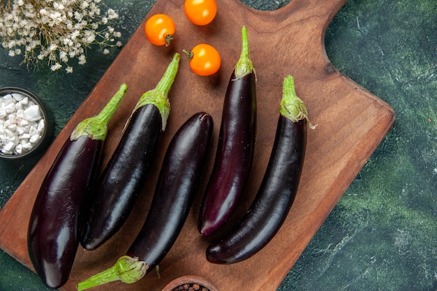 Kostenloses Foto draufsicht schwarze auberginen auf schneidebrett dunkle oberfläche lebensmittelfarbe abendessen frisches salatgemüse