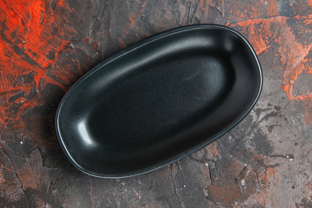 Draufsicht schwarze ovale Platte auf dunkelrotem Hintergrund
