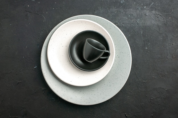 Draufsicht schwarze Tasse Untertasse weiße Platte auf grauer Platte auf dunkler Oberfläche freier Raum