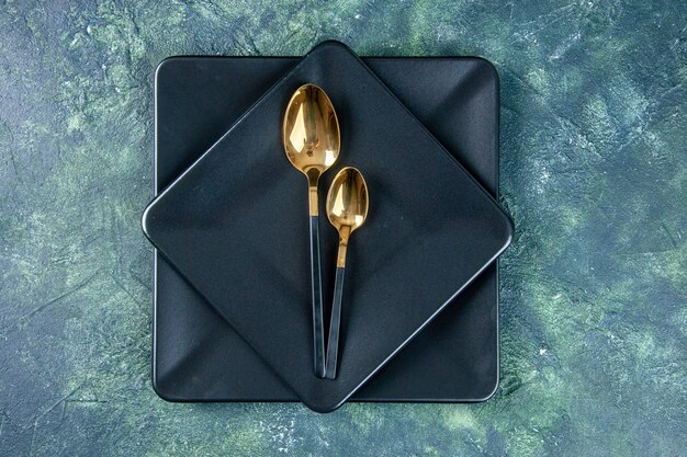 Draufsicht schwarze Teller mit goldenen Löffeln auf dunkler Oberfläche Farbe Essen Restaurant Abendessen Küche Café