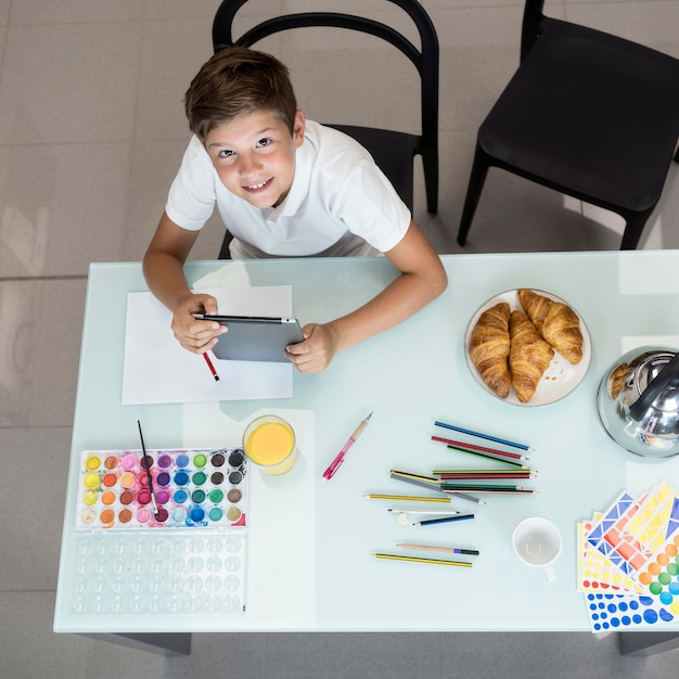 Kostenloses Foto draufsicht smiley-junge, der tablette hält