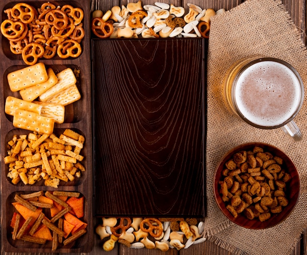 Draufsicht Snacks für Bier Hard Chuck Mini Brezel Salzcracker Fischcracker Chips und weiße Sonnenblumenkerne mit Kopienraum auf Holzhintergrund