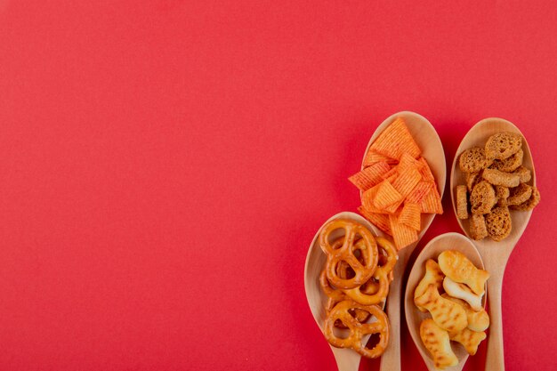 Draufsicht Snacks Paprika-Chips Hartfutter Mini Brezel und Fischcracker auf der linken Seite mit Kopierraum auf rotem Hintergrund