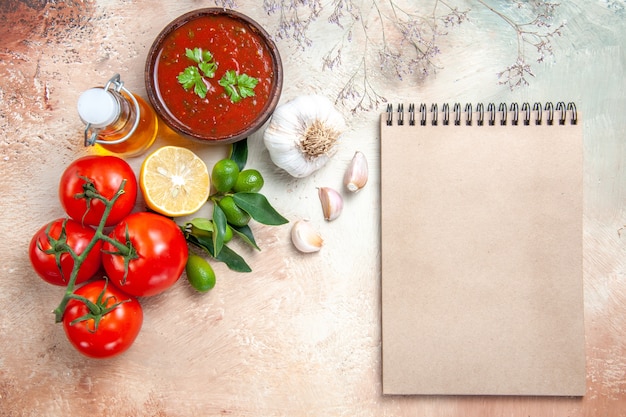 Draufsicht Soße Flasche Öl Tomaten mit Stiel Zitronensauce Knoblauchcreme Notizbuch