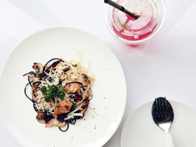 Draufsicht Spaghetti Pasta mit Tomaten und Petersilie auf weißem Tisch.