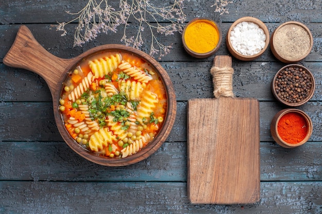 Draufsicht spiralförmige Pastasuppe leckeres Essen mit verschiedenen Gewürzen auf der dunklen Schreibtischsuppe Farbe italienische Pastagericht Küche
