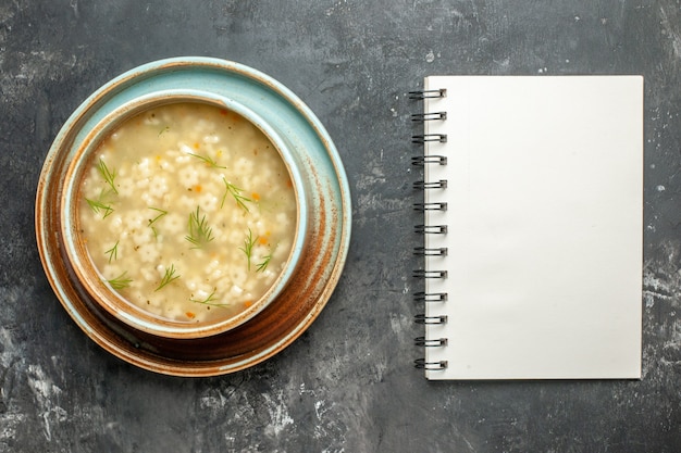 Draufsicht Sternsuppe in Schüssel ein Notizbuch auf dunklem Hintergrund