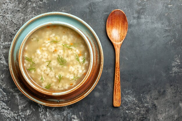 Draufsicht Sternsuppe in Schüssel Holzlöffel auf dunkler Oberfläche