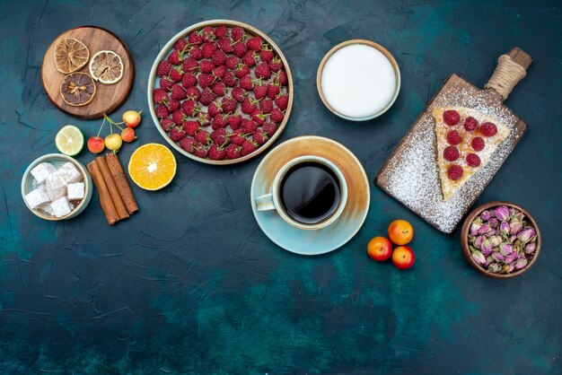 Draufsicht-Stück Kuchen gebacken süß mit Himbeeren und Tee auf dunkelblauem Schreibtisch Beerenzuckerkuchen Kuchen backen Keks