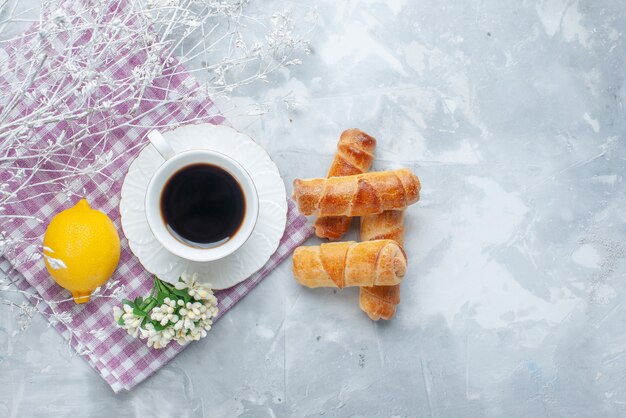 Draufsicht süße Armreifen mit Füllung zusammen mit Kaffee und Zitrone auf dem hellen Hintergrundgebäck backen süßen Kaffee