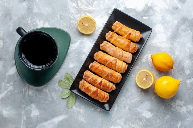 Draufsicht süße Armreifen mit Zitronentasse Tee auf dem Leuchttisch, Gebäckkuchen backen süßen Zucker