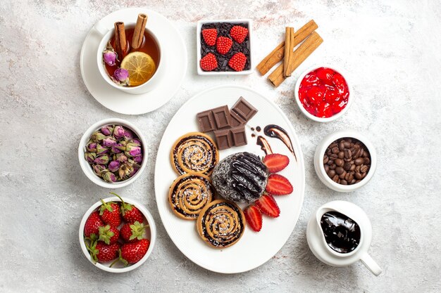 Draufsicht süße Kekse mit Schokoladenkuchen und Tee auf süßem Kekszuckerkuchenplätzchen des weißen Hintergrunds