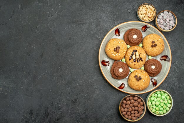 Draufsicht süße Kekse mit Süßigkeiten auf dunkelgrauem Hintergrundzuckerplätzchen süßer Kekskuchen-Tee