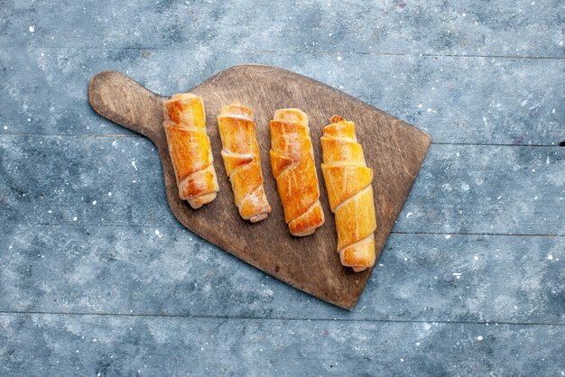 Draufsicht süße köstliche Armreifen mit Füllung auf dem grauen hölzernen Hintergrund süßer Zucker backen Gebäck