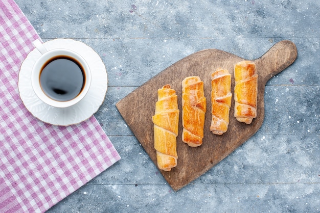 Draufsicht süße köstliche Armreifen mit Füllung zusammen mit Tasse Kaffee auf dem grauen Tisch süßer Zucker backen Gebäckkekskeks