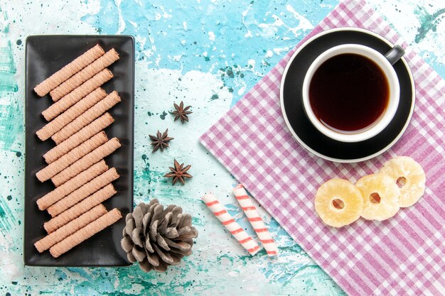 Draufsicht süße lange Kekse mit Tasse Tee und Ananasringen auf dem blauen Hintergrund