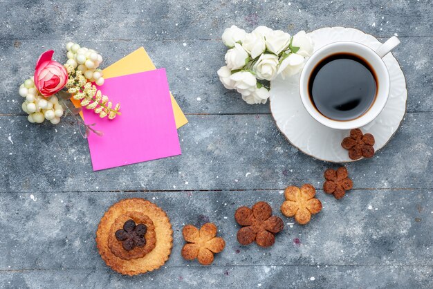 Draufsicht süße leckere Kekse mit Tasse Kaffee der graue Hintergrundplätzchenkeks süß