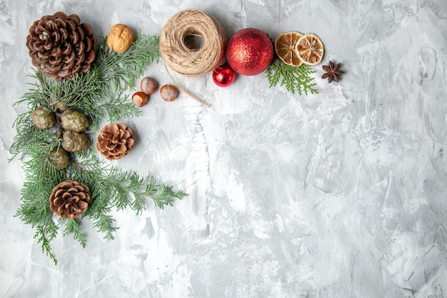 Kostenloses Foto draufsicht tannenbaum zweige kegel weihnachtsspielzeug auf grauem hintergrund