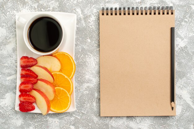 Draufsicht Tasse Kaffee mit geschnittenen Äpfeln Orangen und Erdbeeren auf weißen Hintergrundfrüchten reifen frischen milden