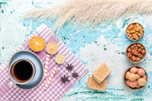 Draufsicht Tasse Kaffee mit Rosinenwaffeln und Konfekt auf dem hellblauen Hintergrundkuchen backen süßen Zuckerkuchenplätzchen
