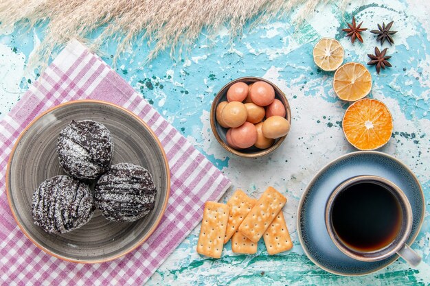 Draufsicht Tasse Kaffee mit Schokoladenglasurkuchen und Crackern auf hellblauem Oberflächenkuchen backen süßen Zuckerkuchenplätzchen