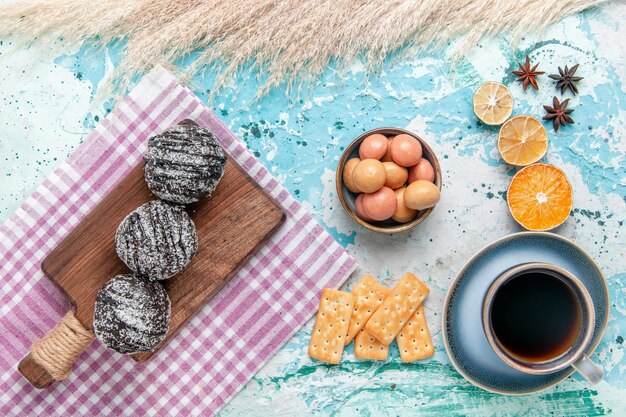 Draufsicht Tasse Kaffee mit Schokoladenglasurkuchen und Crackern auf hellblauem Schreibtischkuchen backen süßen Zuckerkuchenplätzchen