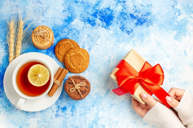 Draufsicht Tasse Tee Geschenk auf weiblicher Hand auf blauem Tisch Freiraum