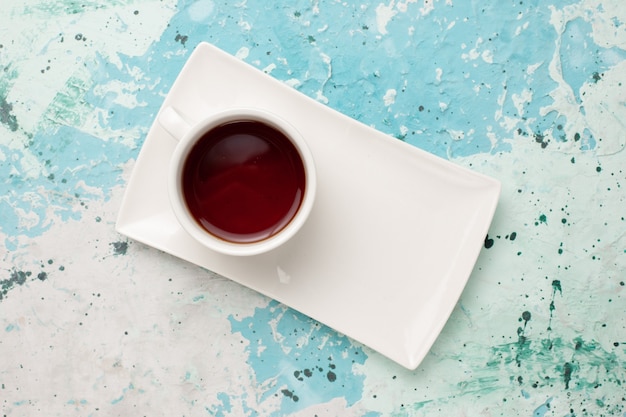 Kostenloses Foto draufsicht tasse tee in tasse und teller auf dem hellblauen schreibtisch