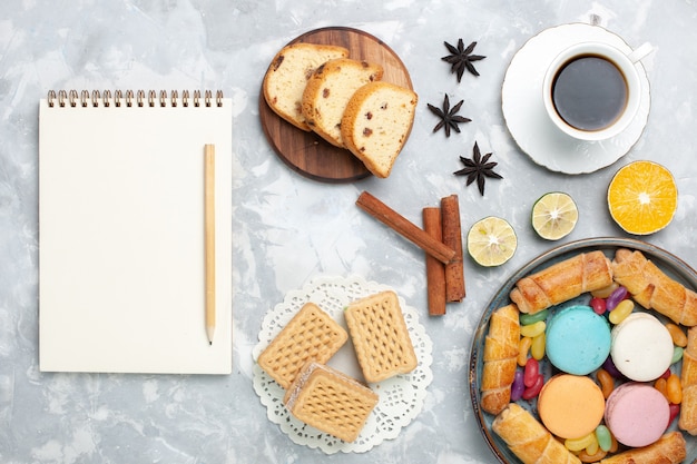 Draufsicht Tasse Tee mit Bagels und Macarons auf Weiß