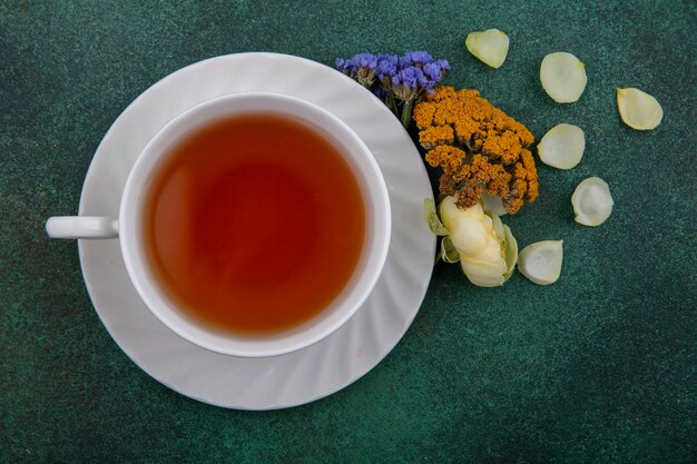 Draufsicht Tasse Tee mit Blumen auf grünem Hintergrund